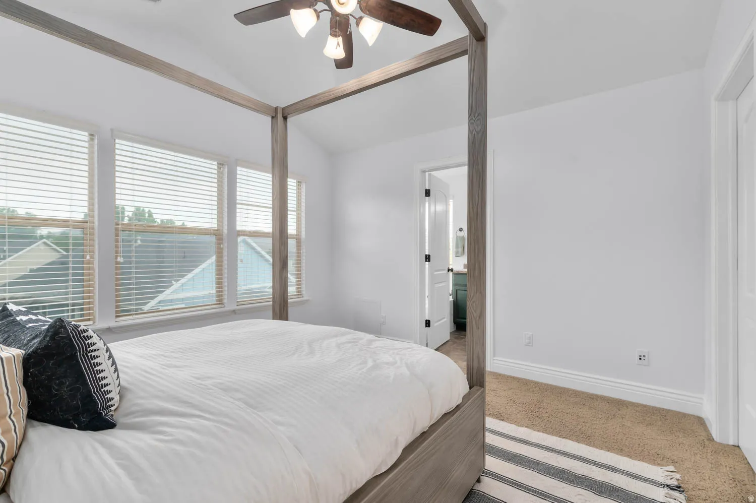 Carpeted room with a vaulted ceiling and a ceiling fan