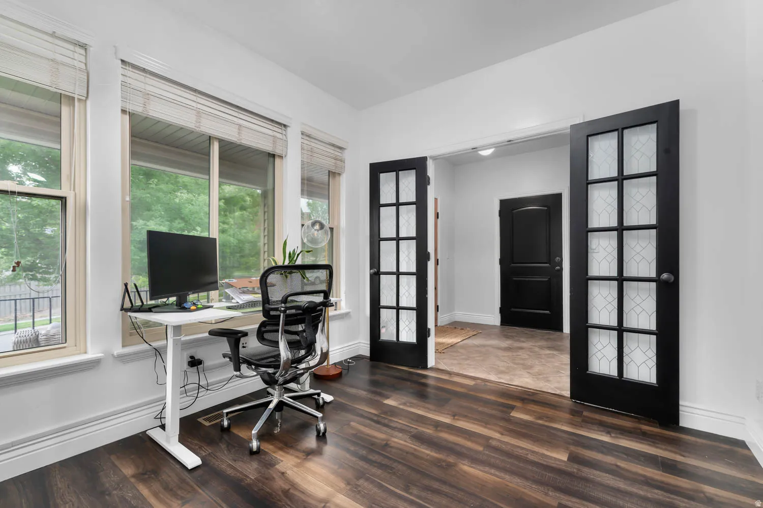 Spacious room featuring rich wood-finish flooring, white baseboards, and bright white walls