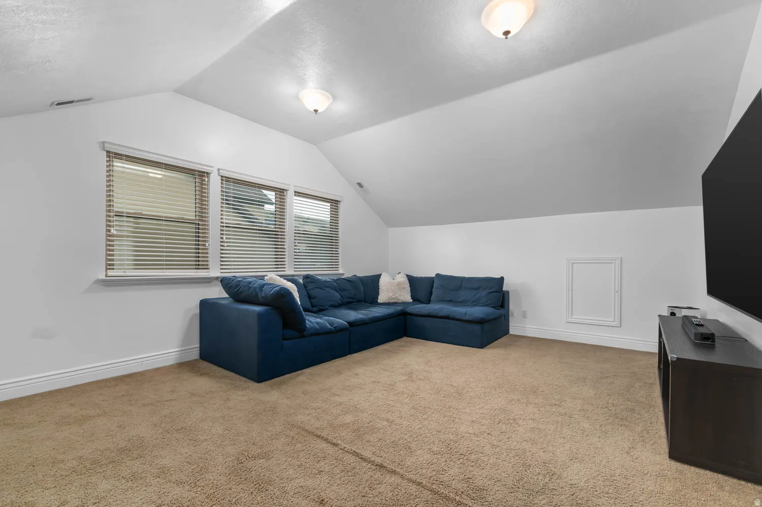 Carpeted bonus room featuring white walls and a sloped ceiling