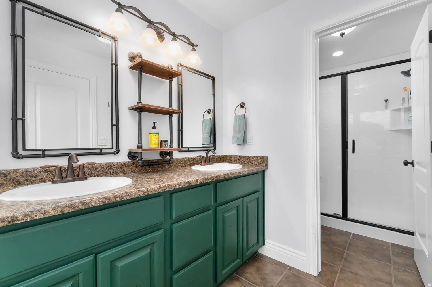 Dual vanity with deep green cabinetry, speckled countertop, and integrated sinks