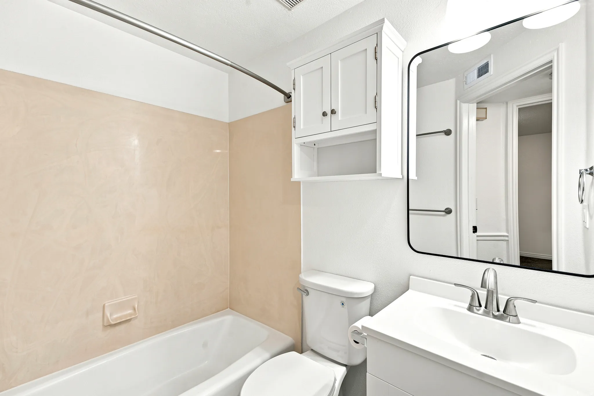 Bathroom featuring a white vanity with integrated sink, chrome-finish faucet, and a rectangular mirror with overhead lighting