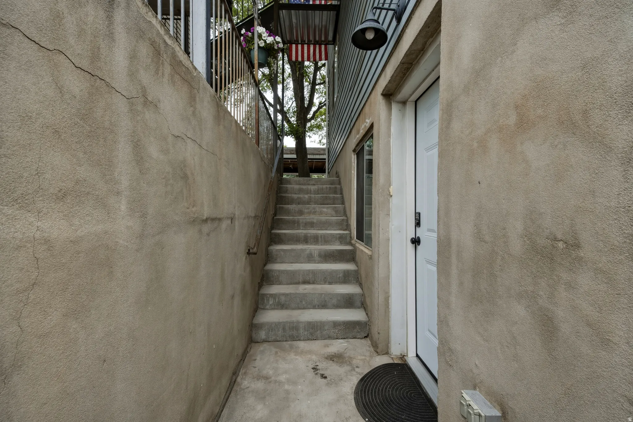 Concrete staircase leading to an upper-level entry with a white door and exterior lighting