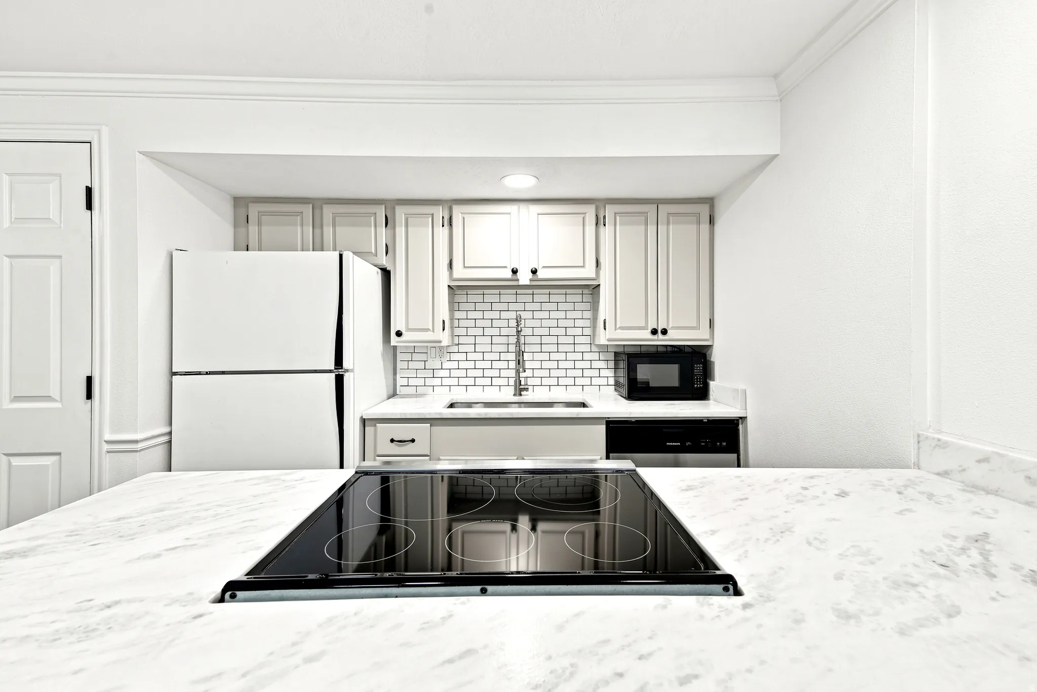 Kitchen featuring white cabinetry, subway tile backsplash, and stone countertops