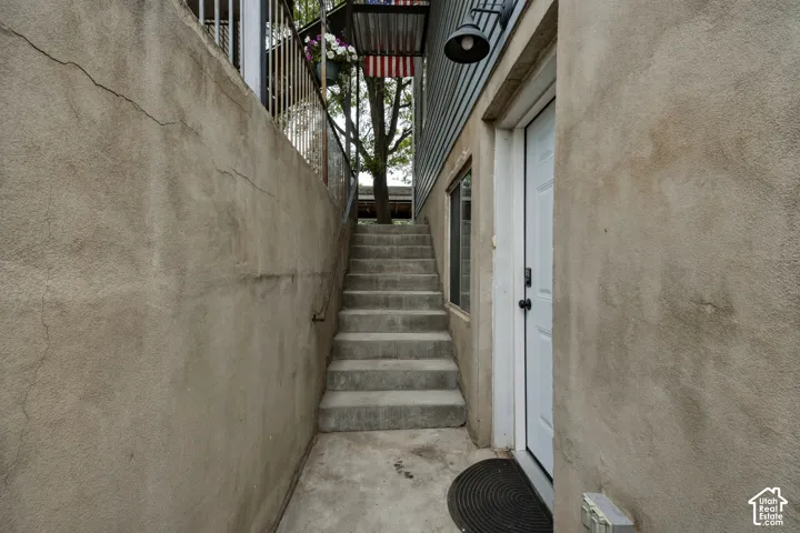 Concrete staircase leading to an upper-level entry with a white door and exterior lighting