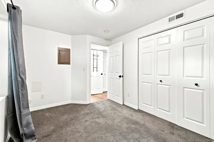 Spacious interior room featuring plush gray carpeting, white walls, and bright overhead lighting