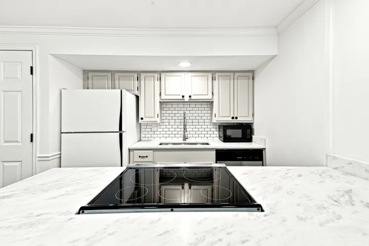 Kitchen featuring white cabinetry, subway tile backsplash, and stone countertops