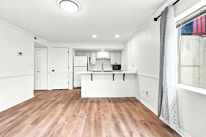 Open-concept living area featuring wood-finish flooring, white baseboards, and crown molding