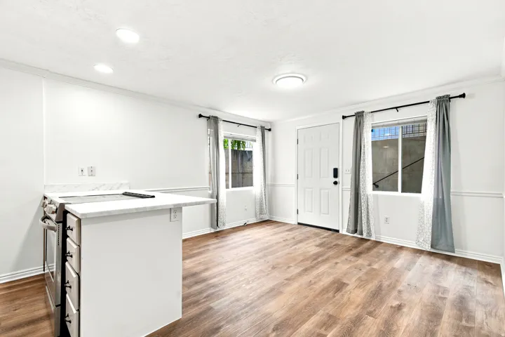 Open-concept living space featuring wood-finish flooring, white walls with wainscoting, and recessed lighting