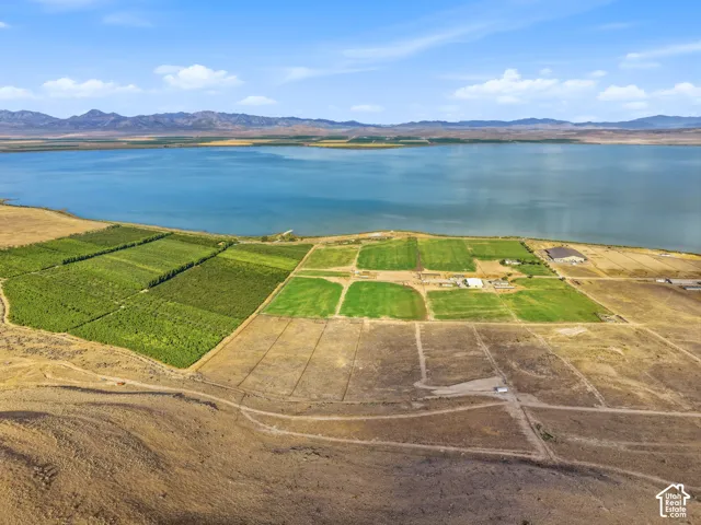 Expansive property featuring a large body of water, distant mountains, cultivated fields, and multiple structures