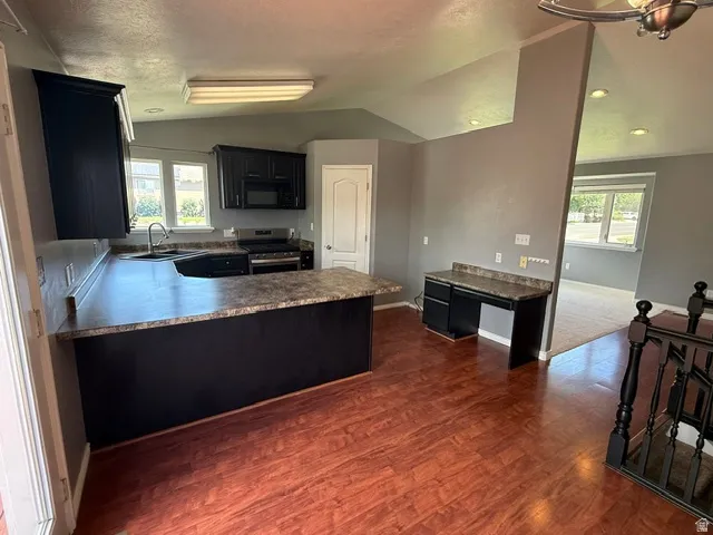Kitchen featuring dark cabinetry, dark countertops, built-in desk, wood-finish flooring, and recessed lighting