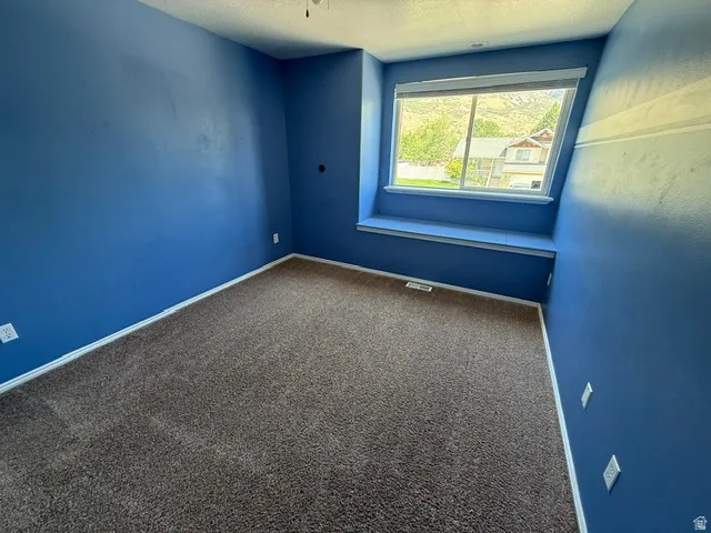 Room with a built-in window bench, brown carpet flooring, and blue painted walls with white trim