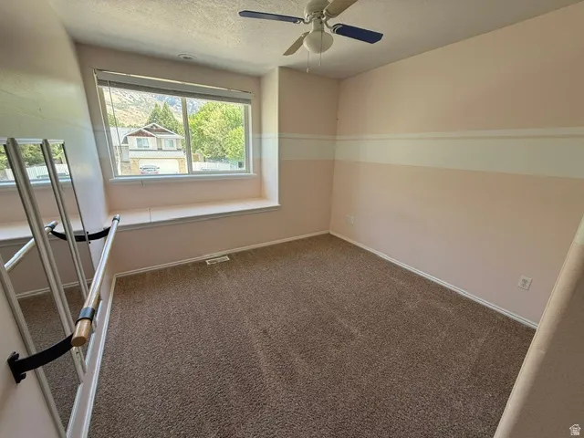 Carpeted room featuring a window seat, a ceiling fan, and a large window with mountain scenery