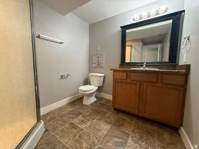 Bathroom featuring a wood-finish vanity with a stone-look countertop, a framed mirror, and overhead lighting