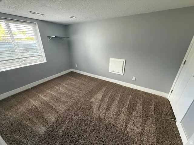 Room featuring gray painted walls, brown patterned carpet, and white baseboards