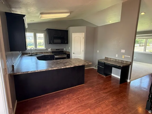 Kitchen featuring dark cabinetry, dark countertops, wood-finish flooring, and built-in desk area