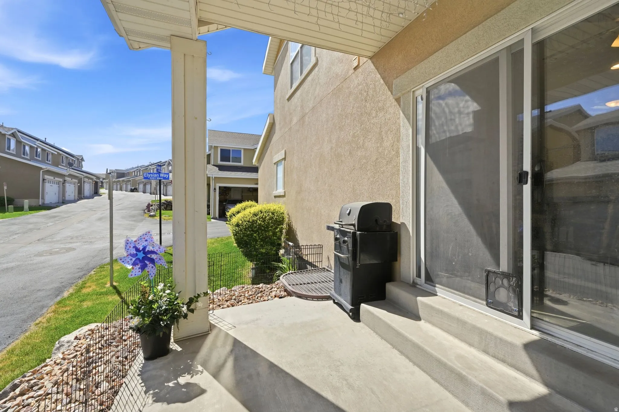 Concrete patio with two steps, covered by an overhang, featuring an exterior sliding glass door
