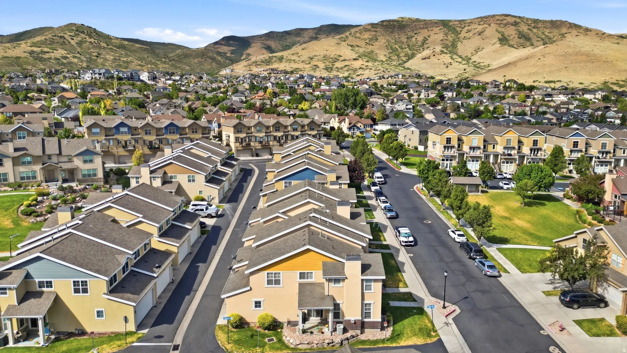Residential community featuring multiple housing styles including townhomes and detached homes, tree-lined streets, and open green spaces