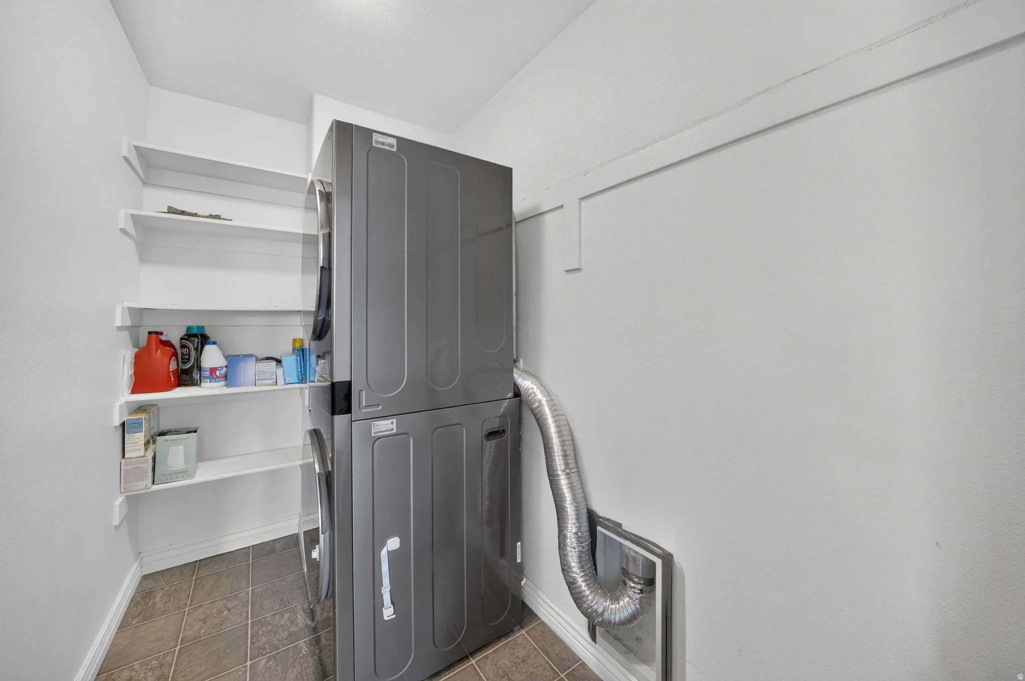 Dedicated laundry area featuring stacked appliances and integrated white shelving