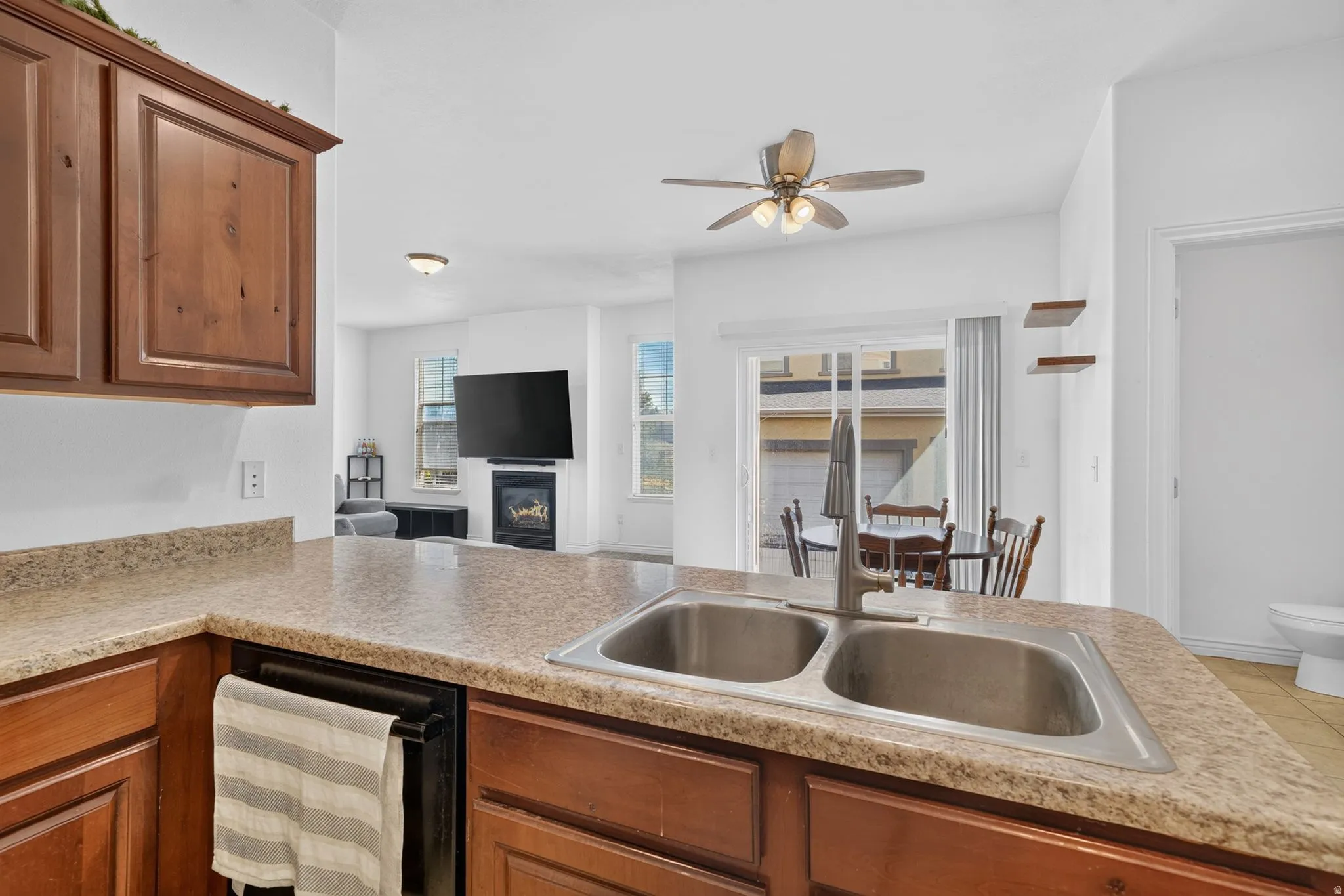 Kitchen featuring wood-finish cabinetry, speckled countertops, and a dual-basin stainless steel sink with a gooseneck faucet