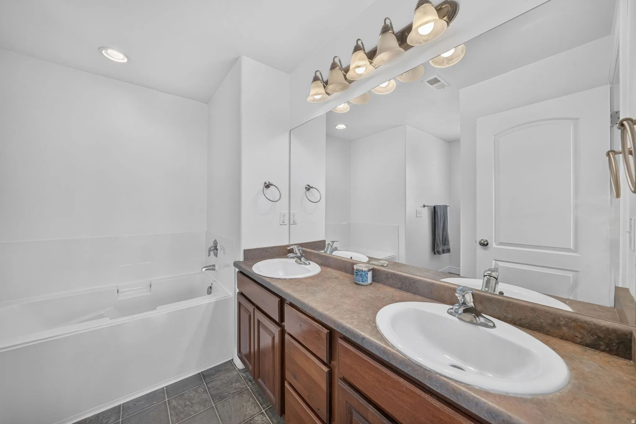 Bathroom with dual vanity featuring integrated sinks, ample counter space, and warm wood-finish cabinetry