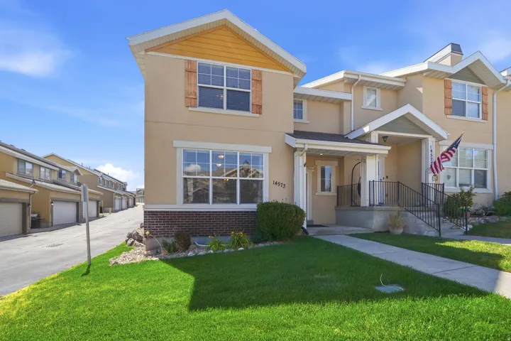 Two-story townhome featuring a stucco exterior with brick accents