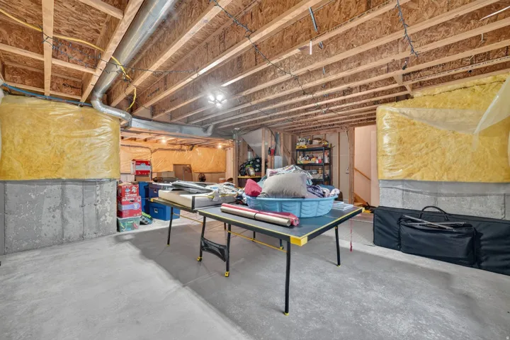 Unfinished basement with concrete flooring, exposed wood joists, and concrete foundation walls