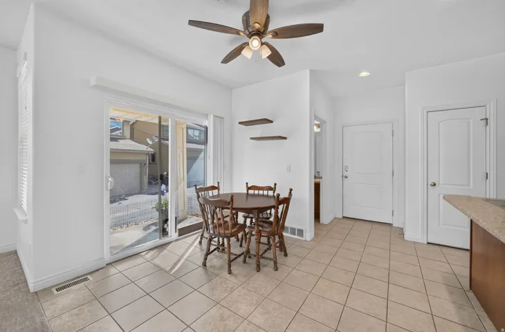 Tiled flooring throughout the dining area, featuring sliding glass door access to the exterior, and a ceiling fan with integrated lighting