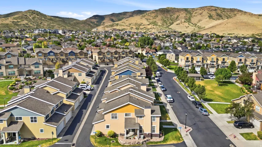 Residential community featuring multiple housing styles including townhomes and detached homes, tree-lined streets, and open green spaces