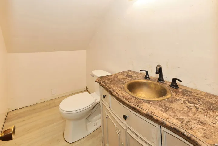 Bathroom featuring a light wood-finish floor, a white toilet, and a vanity with a patterned countertop