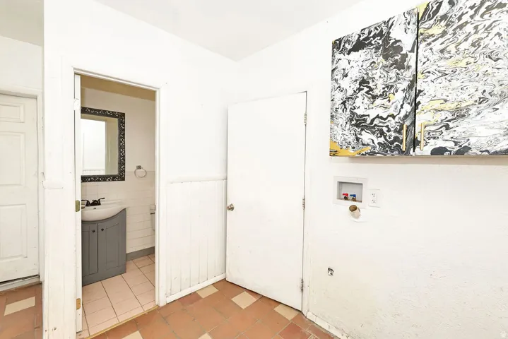 Utility area featuring terra cotta-toned floor tiles and laundry hookups