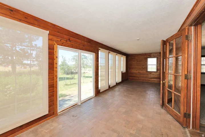 Sunroom featuring wood-paneled walls, multiple sliding glass doors, a single window, and a tile floor