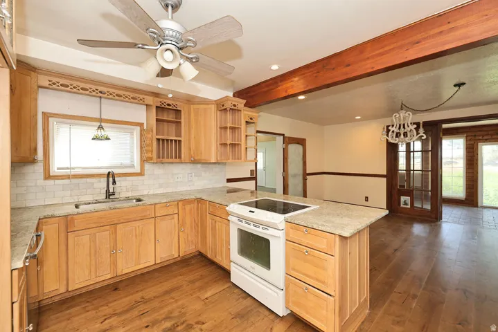 Open-concept kitchen with light wood cabinetry, stone countertops, and wood-finish flooring