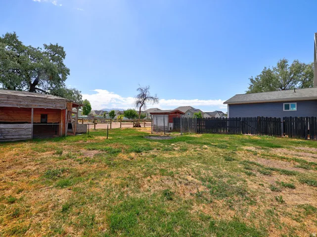 Expansive property with a wood-fenced enclosure and an additional small outbuilding