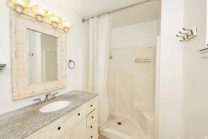 Bathroom vanity with a speckled countertop, undermount sink, and brushed nickel faucet