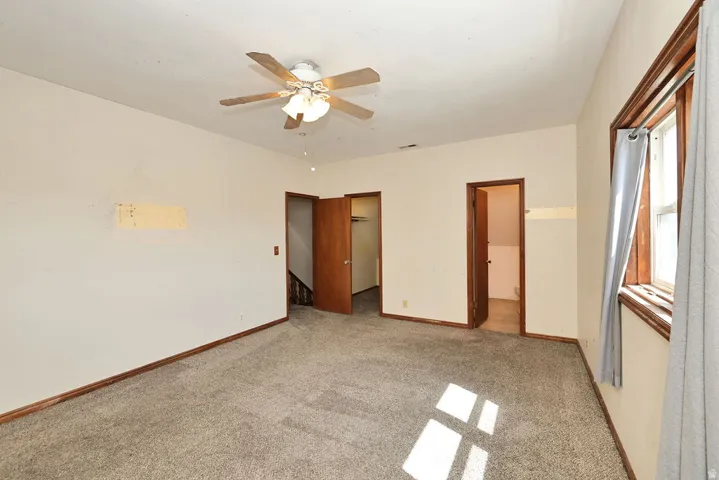 Room featuring neutral-toned carpet flooring, light wall paint, and natural wood trim