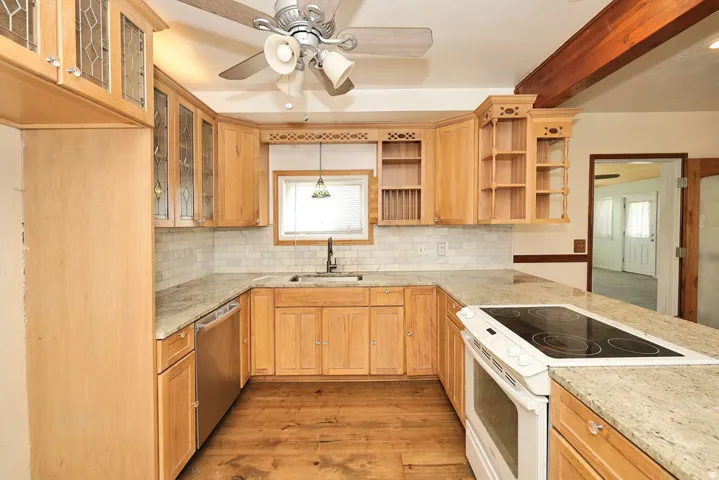 U-shaped kitchen featuring wood-finish cabinetry, light-toned countertops, a tile backsplash, and wood-finish flooring