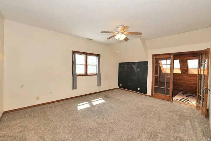 Spacious room featuring neutral carpeting and a ceiling fan
