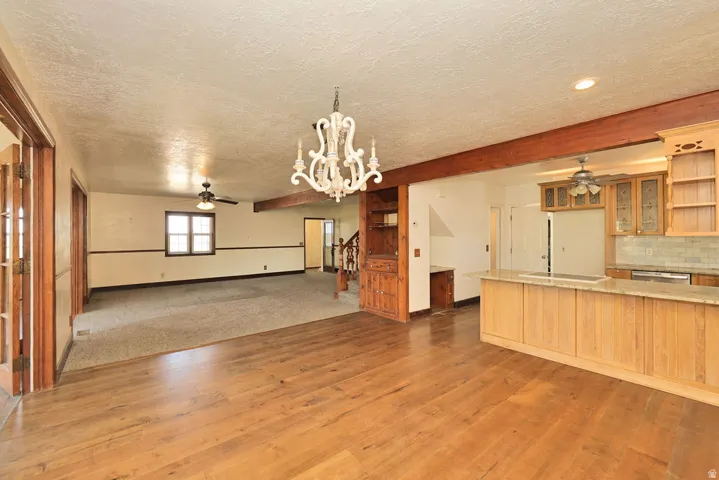 Open-concept living space featuring wood-finish flooring, a decorative chandelier, and a built-in wooden shelving unit