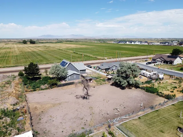 Spacious property featuring a gray house with solar panels, a large open field, and mature trees