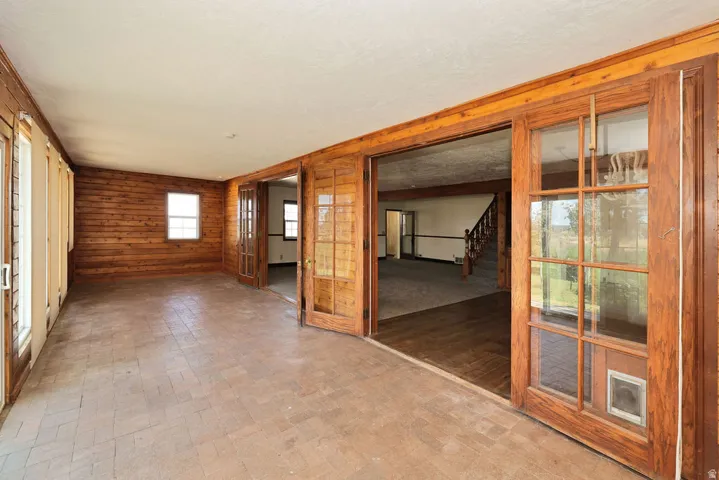 Spacious sunroom featuring brick-patterned flooring and natural wood paneling