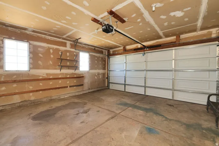 Spacious garage featuring a concrete floor, two windows, built-in shelving, and a white panel garage door
