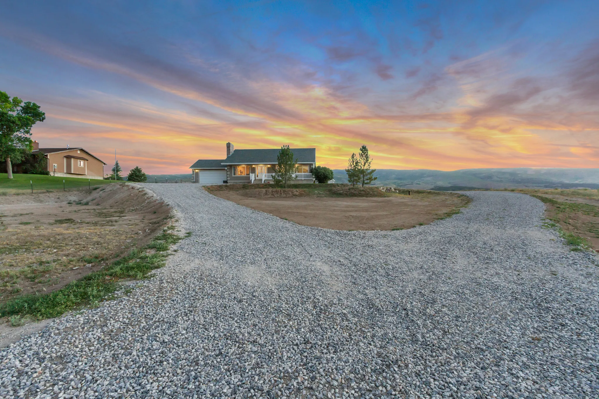 Spacious gravel driveway leading to a single-story residence with an attached garage and front porch
