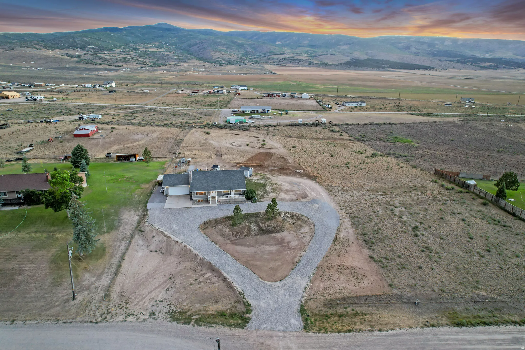 Expansive property featuring a single-story residence, gravel driveway, and surrounding open terrain