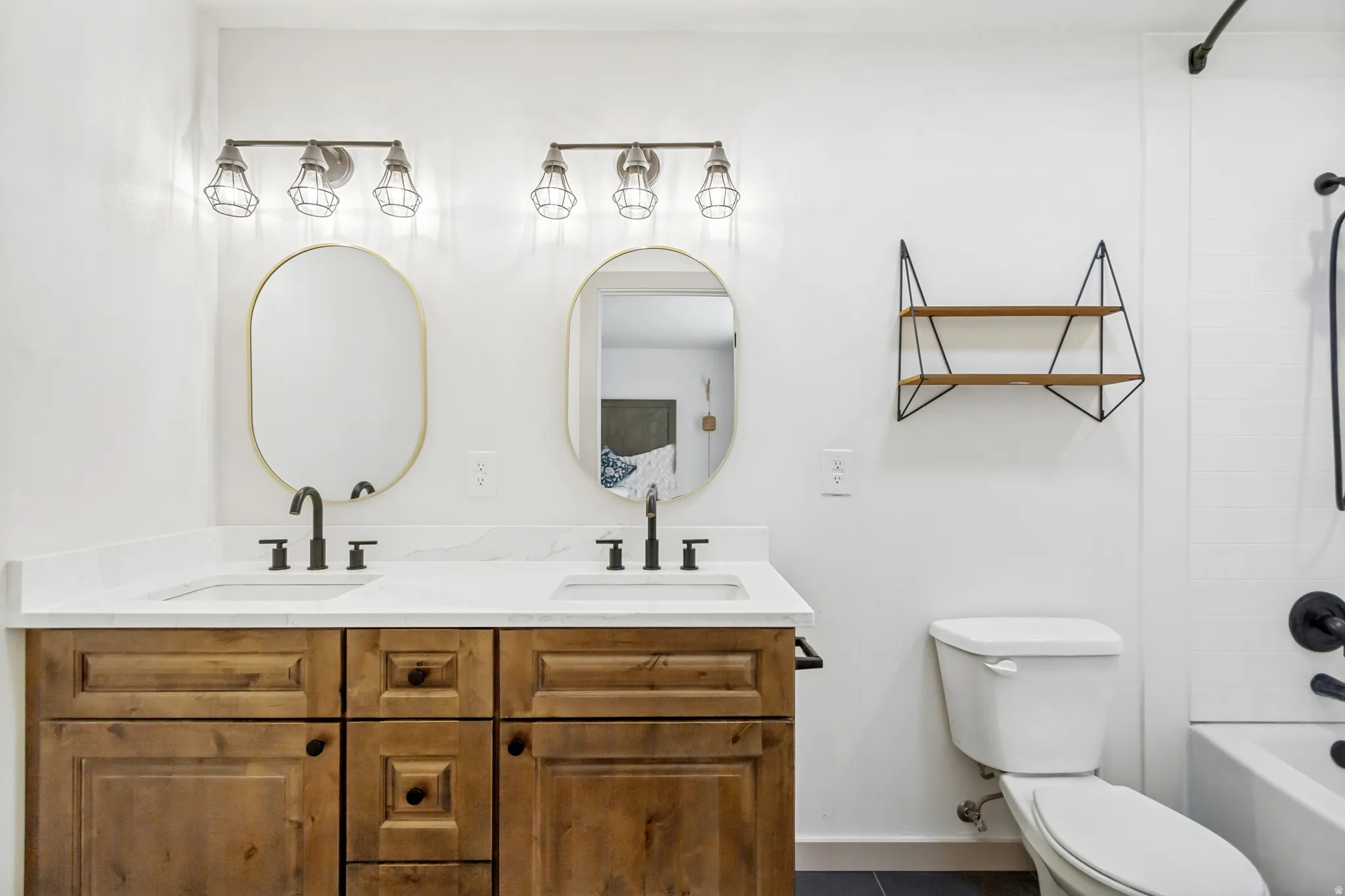 Double vanity with wood-finish cabinetry, white countertop, and dual oval mirrors