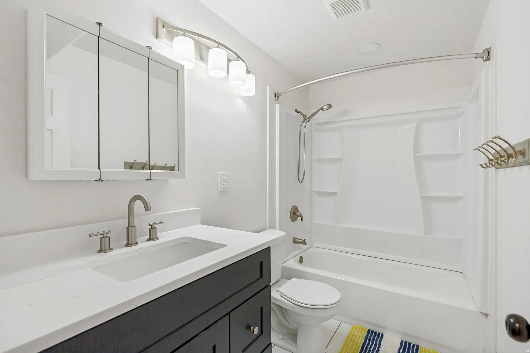 Bathroom featuring a dark wood-finish vanity with an integrated sink, brushed nickel faucet, and a wall-mounted medicine cabinet