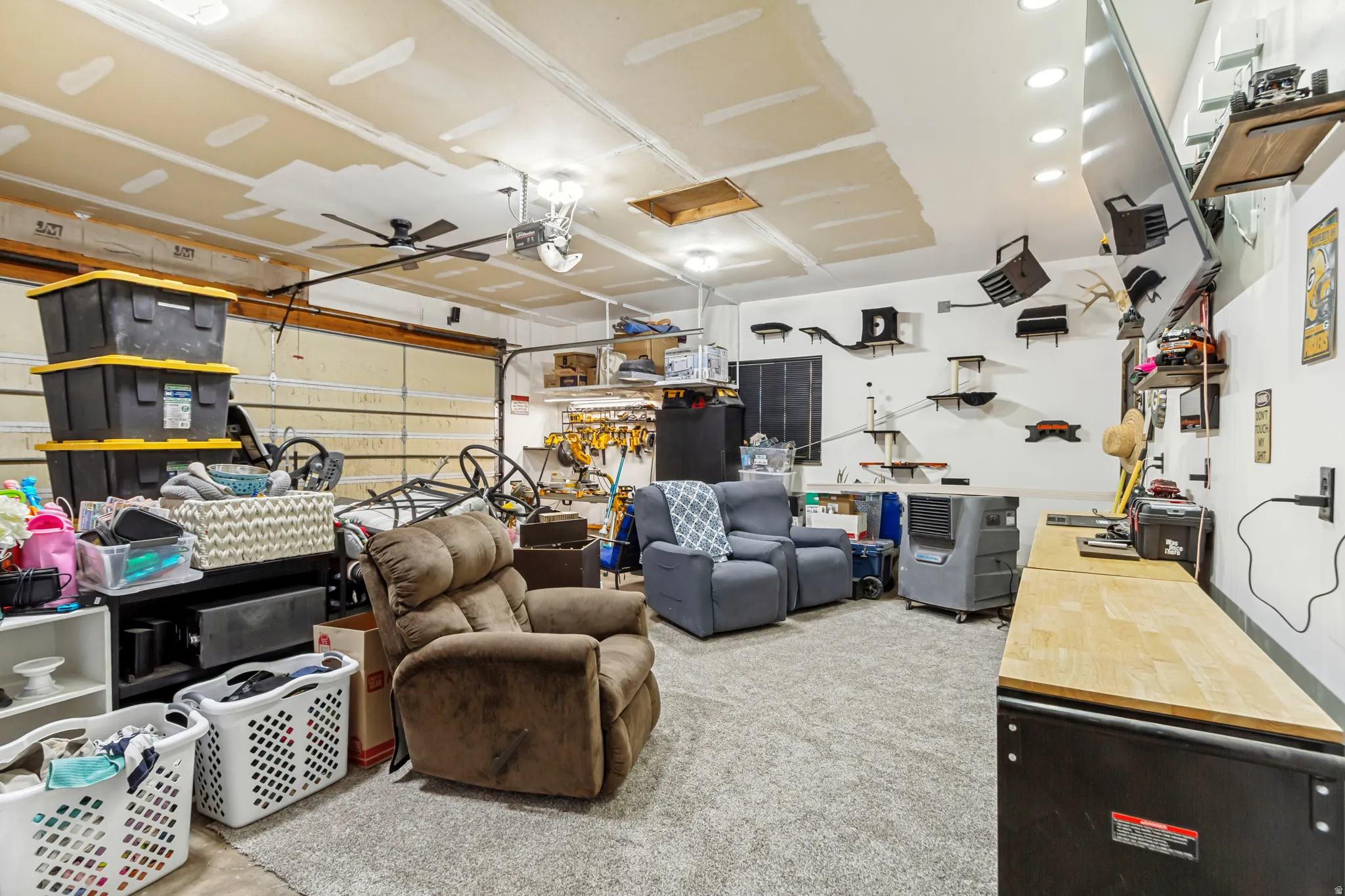 Spacious garage featuring an overhead door, built-in workbench, wall-mounted shelving, and overhead lighting