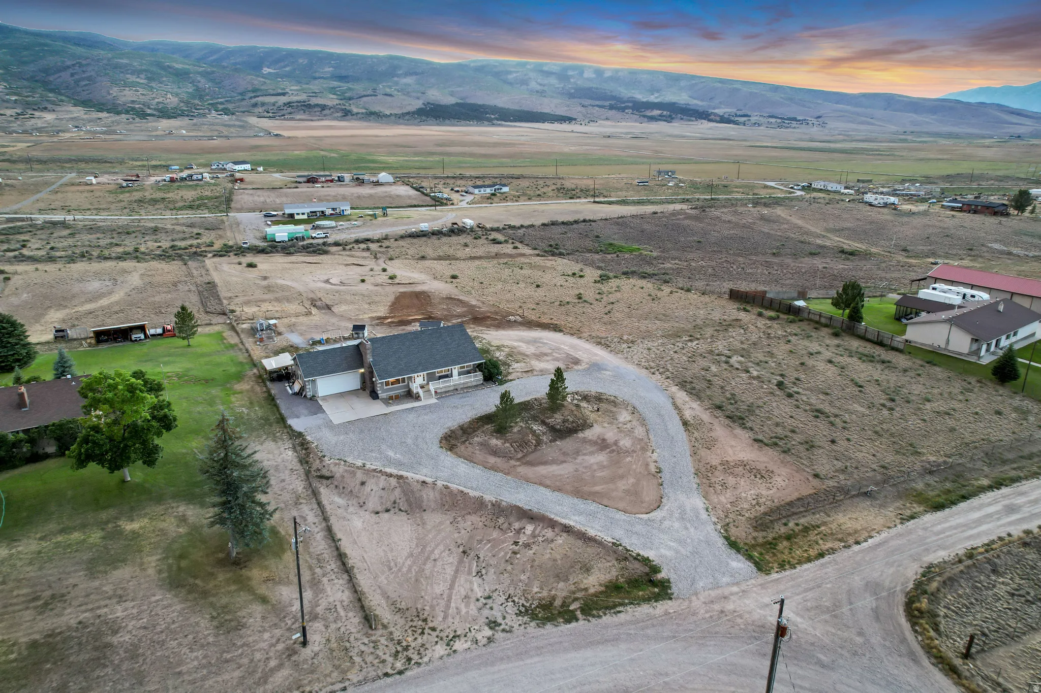 Property featuring a gravel drive, attached garage, covered porch, and expansive land
