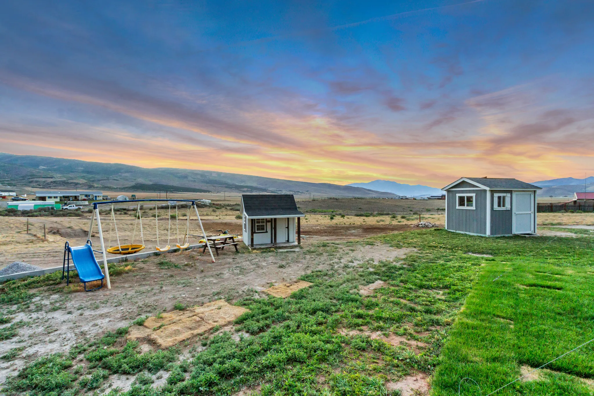 Expansive outdoor grounds featuring varied terrain, a freestanding shed, and distant mountain scenery