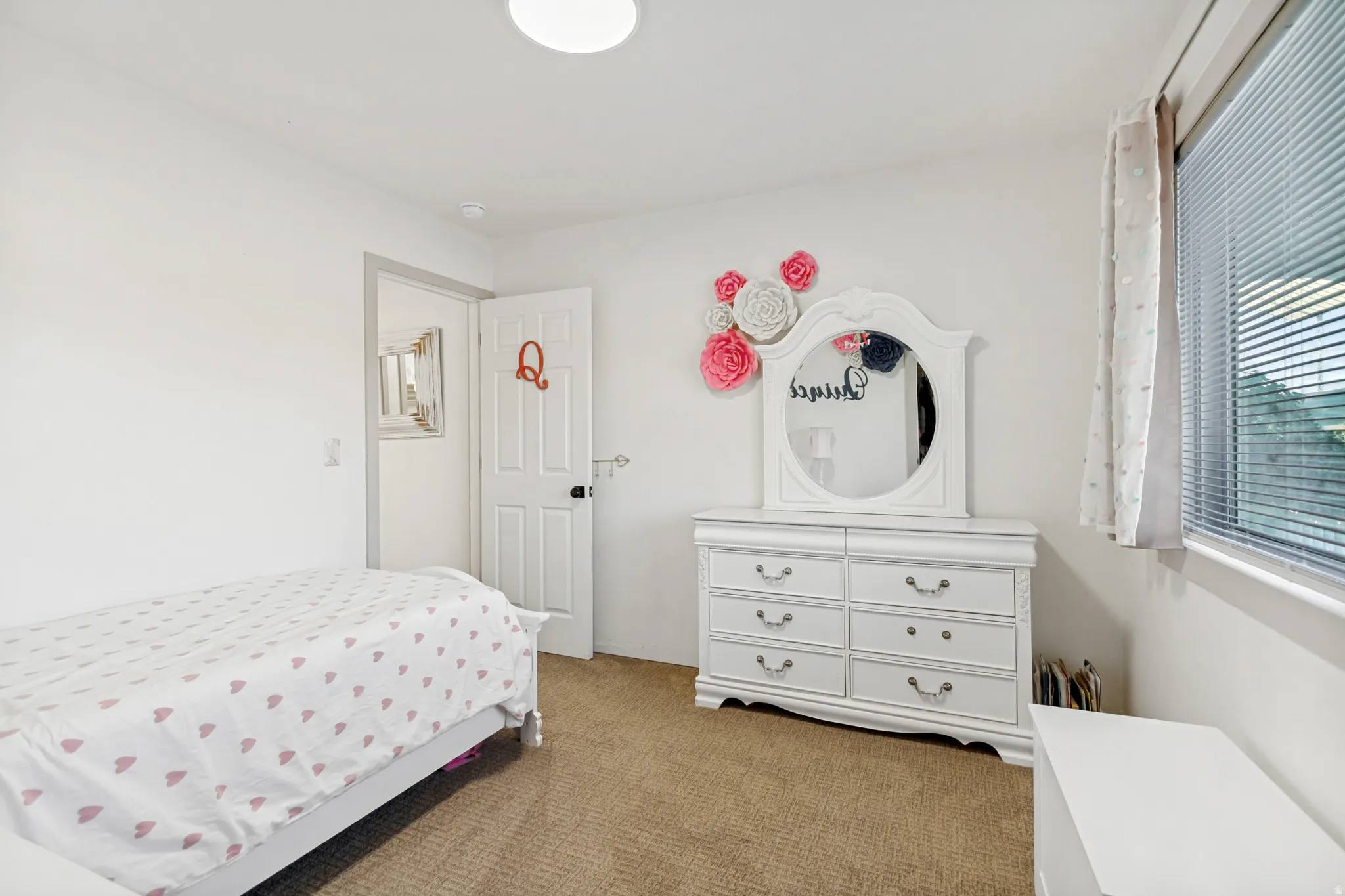 Bedroom with neutral-toned carpeting, white walls, and a white interior door with dark hardware