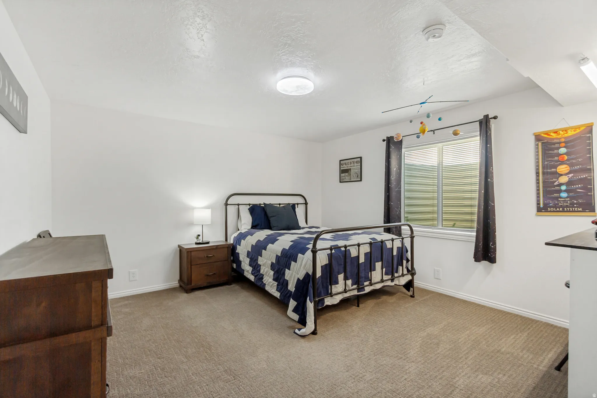 Carpeted room featuring a window with blinds, white baseboards, and a ceiling light fixture